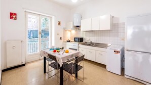 A compact kitchen with white cabinets, a microwave, a sink, and a refrigerator. - House Rondinella Genova City Center (Genoa)