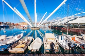A marina with multiple boats docked, a clear blue sky, and a modern bridge structure. - House Rondinella Genova City Center (Genoa)