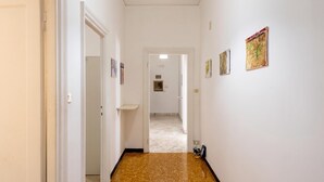 A hallway with white walls, a speckled brown floor, and a door at the end. - House Rondinella Genova City Center (Genoa)