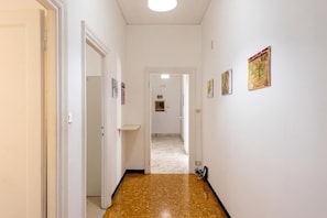 A hallway with white walls, a speckled brown floor, and a door at the end. - House Rondinella Genova City Center (Genoa)