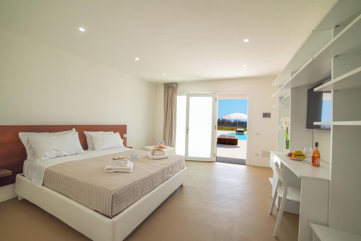 A modern hotel room with a large bed, a desk, and a TV.