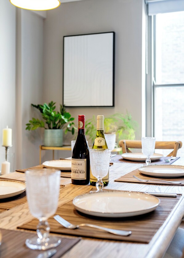Una mesa de comedor preparada con platos, cubiertos y botellas de vino.