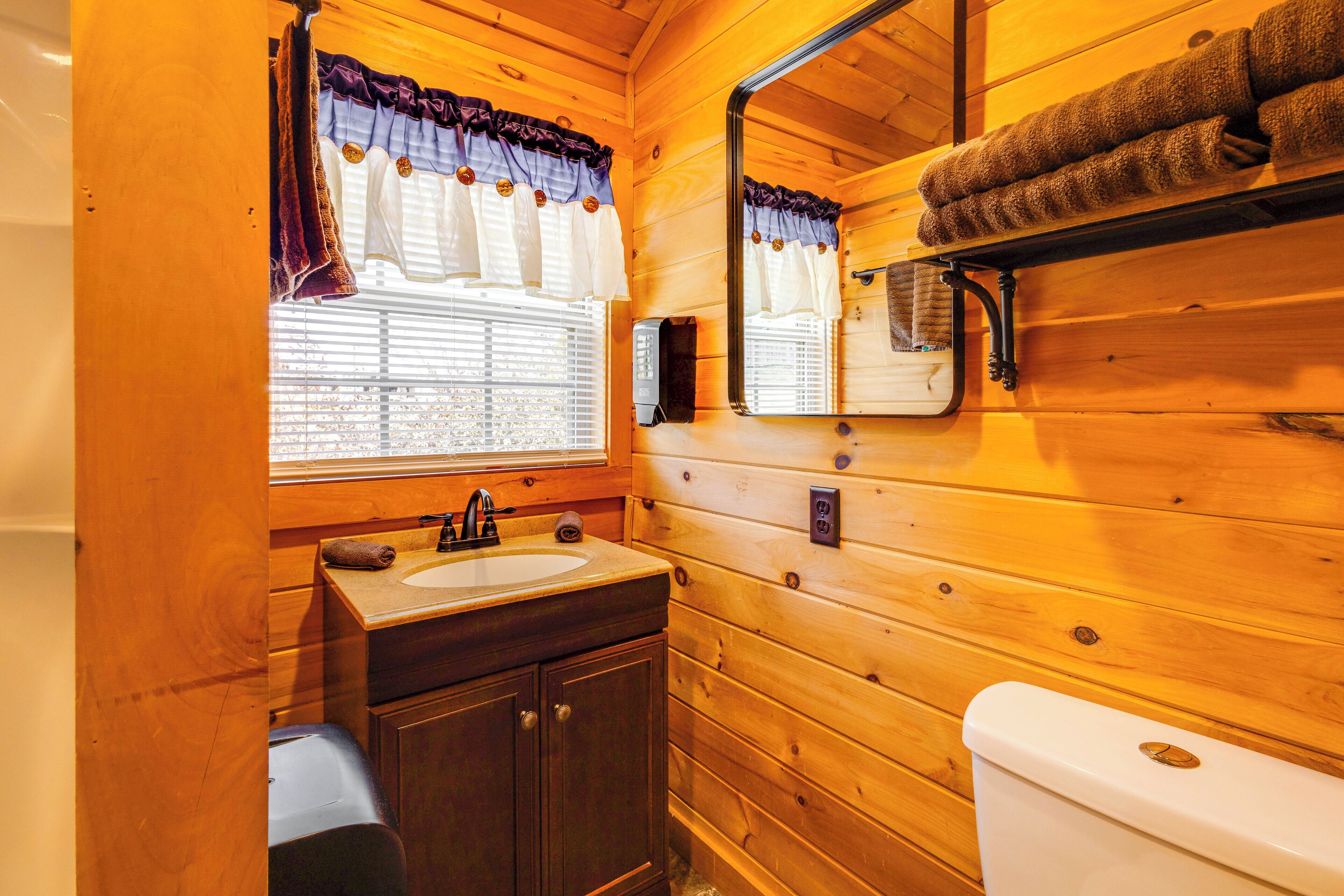 Ein Badezimmer einer Holzhütte mit Waschbecken, Spiegel und Toilette.