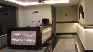 Un área de recepción con mostrador, señalización de ascensor y ventilador de techo.