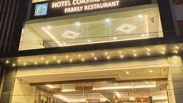 Un hotel con un cartel que indica Hotel Coastal Grand Inn y un restaurante familiar.