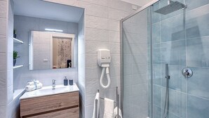 A modern bathroom with a glass shower enclosure, a wooden vanity, and a mirror above the sink.