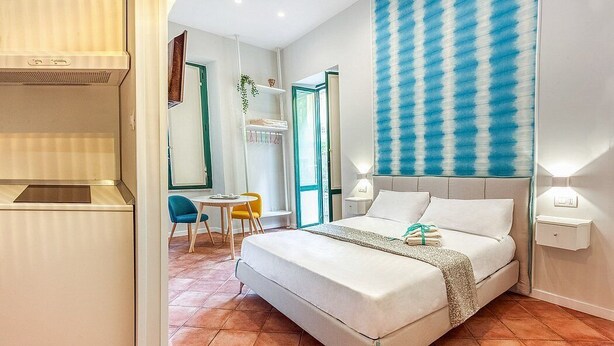 A modern hotel room with a bed, a desk, and a chair.