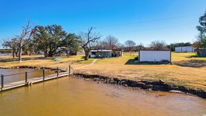 A riverside property with a dock, a small house, and a shed. - Dock & Patio: Possum Kingdom Lake House (Graford)