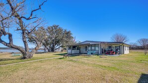 A single-story house with a porch, a lawn, and a flag. - Dock & Patio: Possum Kingdom Lake House (Graford)