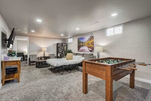 A cozy room with a bed, a foosball table, a desk, and a TV.