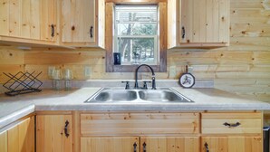 A wooden cabin kitchen with a double sink, wooden cabinets, and a window with blinds. - 31 Mi to Louisville: Cabin on 235 Acres! (La Grange)