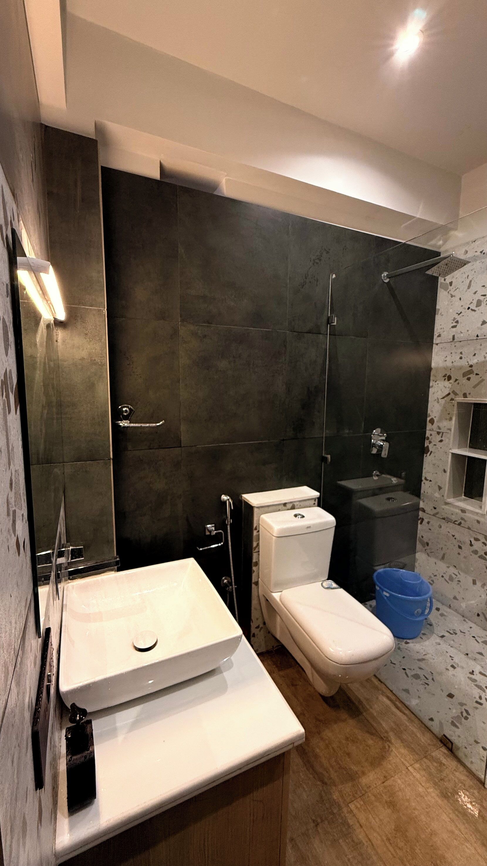 Une salle de bain moderne avec un grand miroir, un lavabo blanc, des toilettes et un espace douche.
