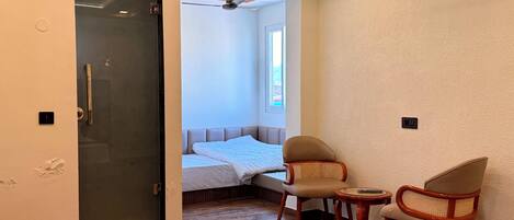 A bedroom with a bed, a window, and a seating area with two chairs and a small table.