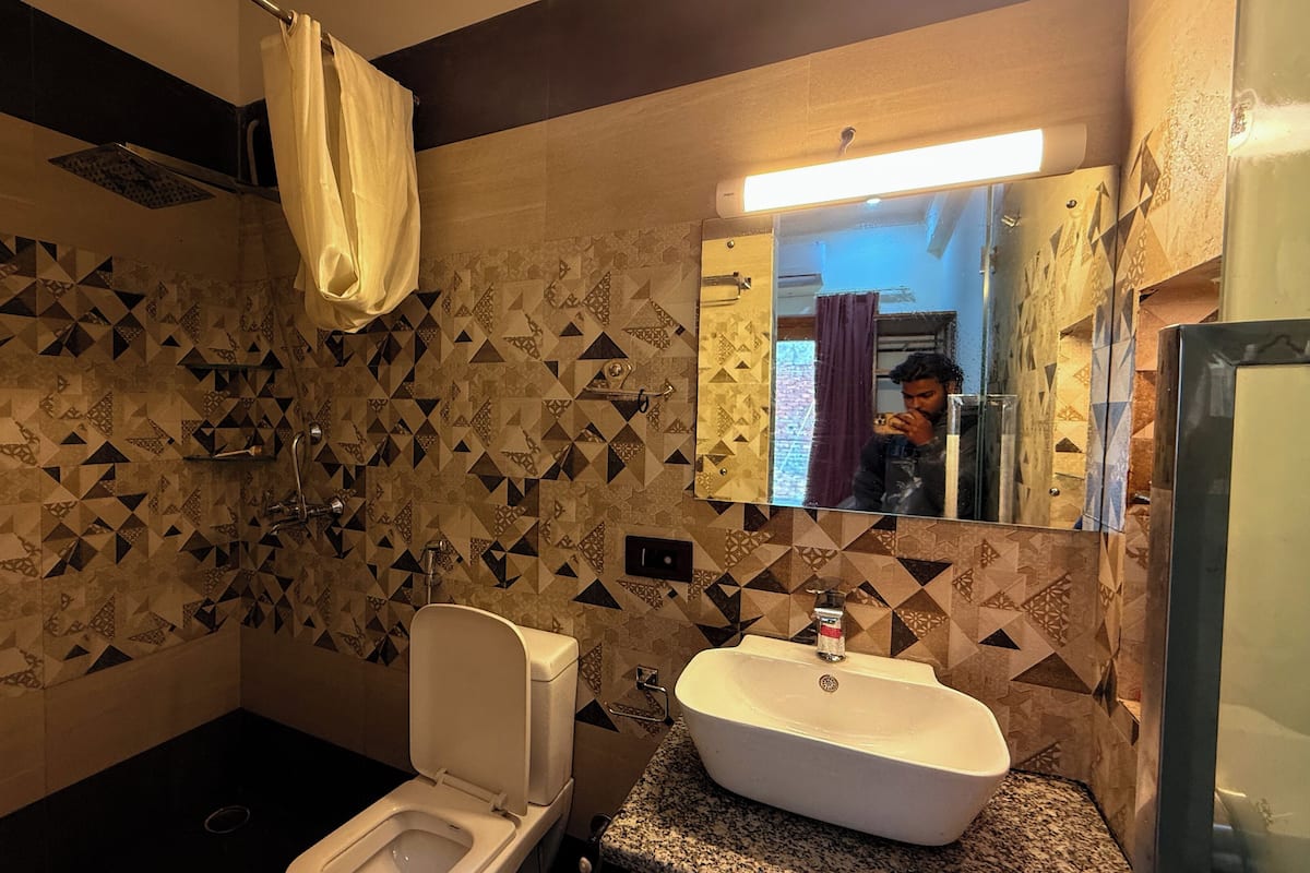 A bathroom with a toilet, sink, and shower. The walls have a geometric tile pattern.