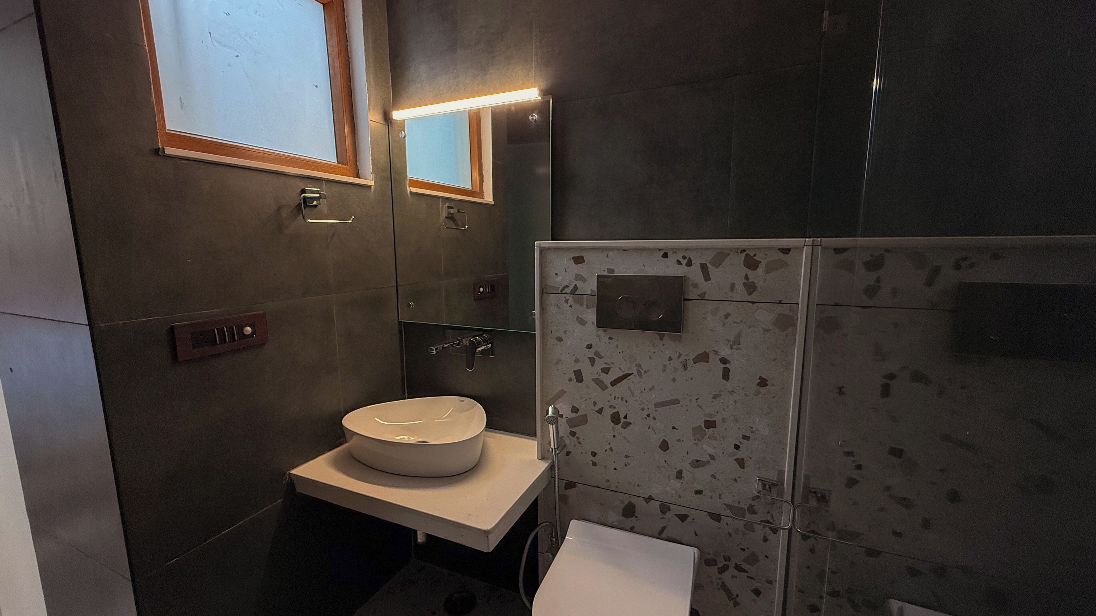 A modern bathroom with a round sink, a mirror, and a shower area.