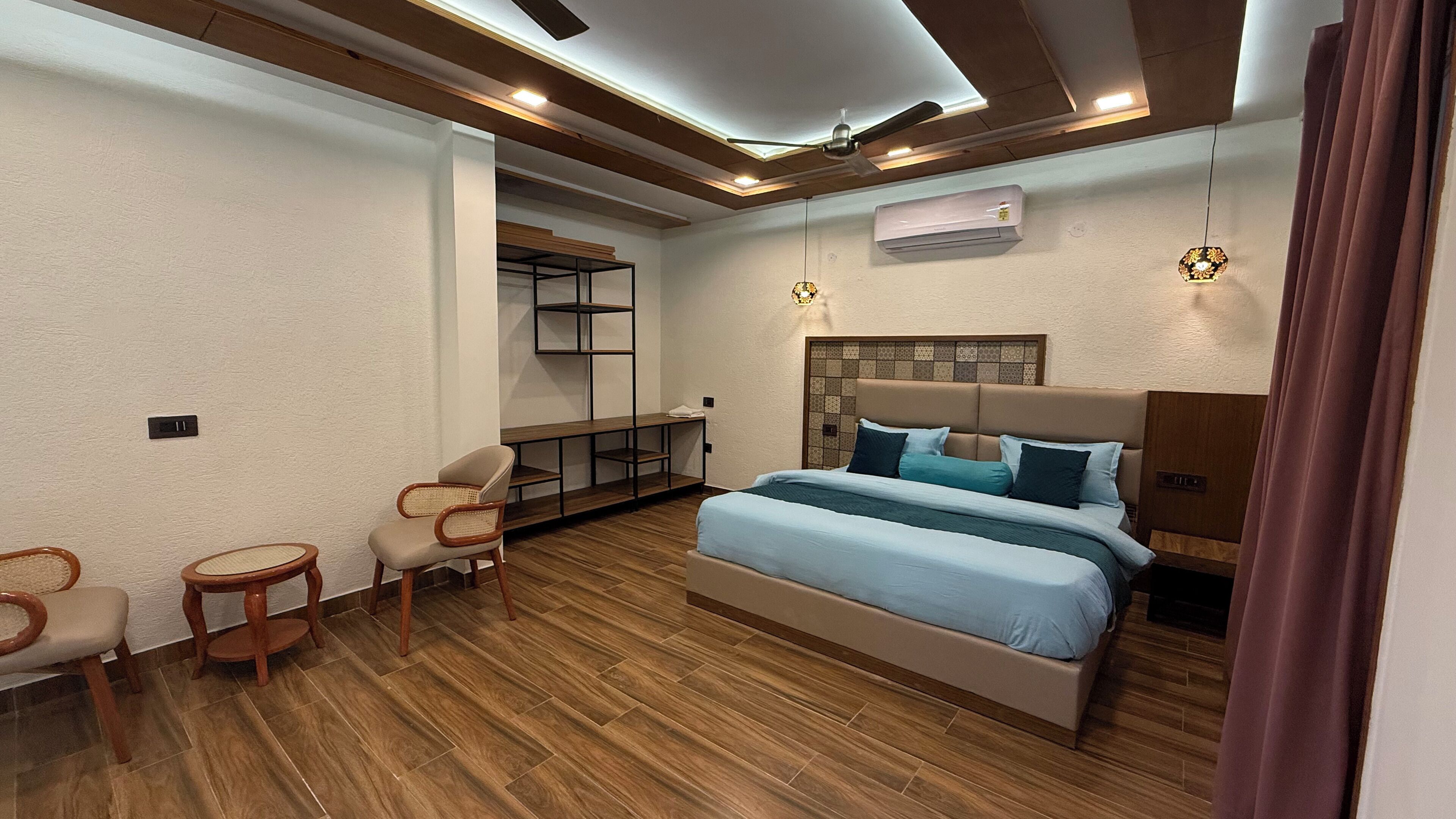 Quarto moderno com uma cama grande, um pequeno espaço para sentar e uma estante embutida.