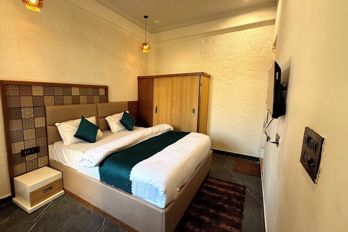 A neatly arranged bedroom with a bed, bedside tables, a wardrobe, and a television mounted on the wall.