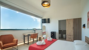Ein modernes Hotelzimmer mit einem großen Bett, einem Schreibtisch, einem Sessel und einem Kleiderschrank.