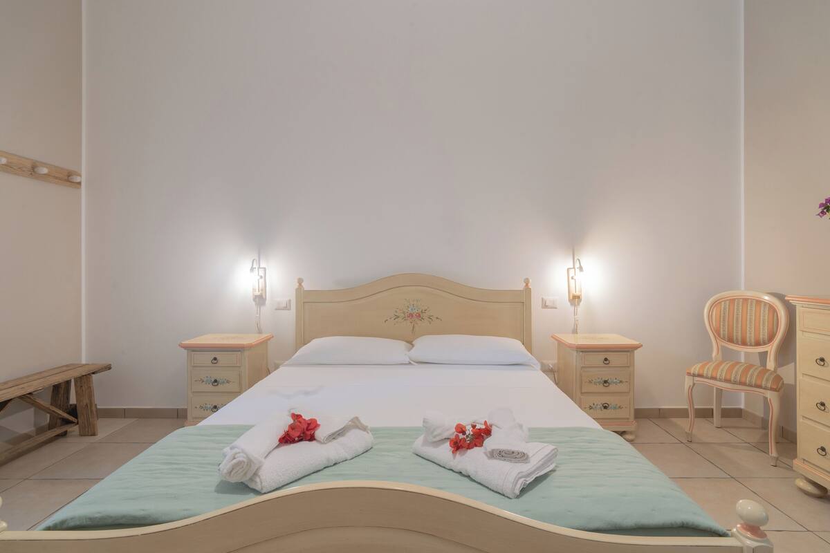 Un lit bien fait avec deux oreillers, une table de chevet avec une lampe, une chaise et une commode.