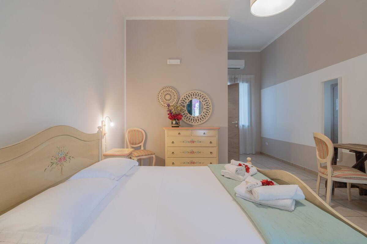 Une chambre à coucher avec un lit, une commode, une chaise et une table.