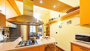 A modern kitchen with a central island, stainless steel appliances, and a built-in microwave. - Graceful Home Genova City Center (Genoa)