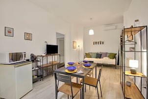 Un espacio habitable compacto con kitchenette, comedor y zona de estar.