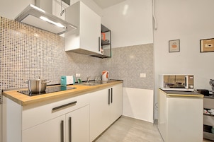 Una cocina moderna con armarios blancos, encimera de madera, horno empotrado y microondas.