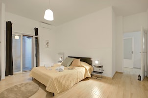 Un dormitorio con cama, mesitas de noche, lámpara, radiador y puerta corrediza de cristal.