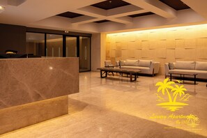 Een moderne lobby met een receptiebalie, banken en een muren met een patroon.