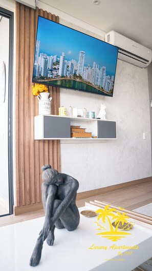 A modern living room with a mounted flat-screen TV, a sculpture, and a decorative vase.