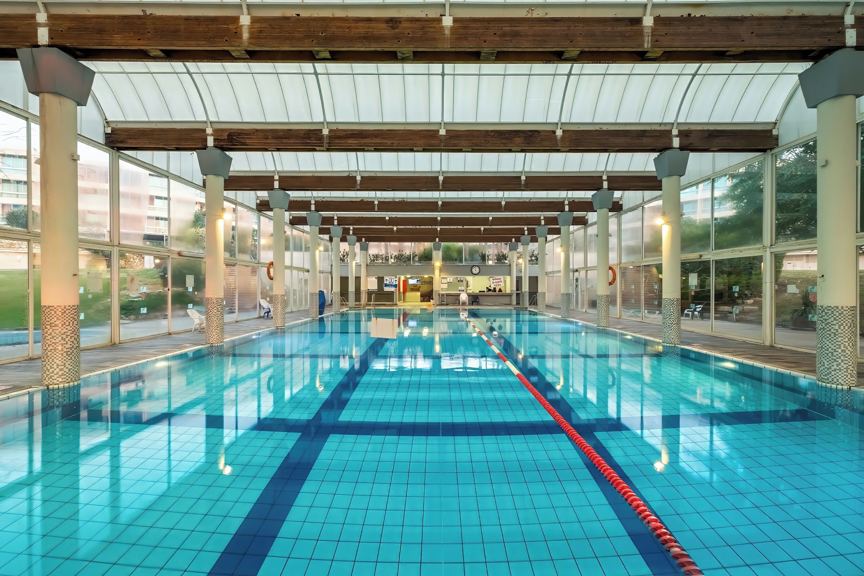 En inomhuspool med tydliga banor, ett tak som skyddar mot väder och vind samt utsikt över det omgivande området.