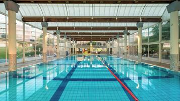 En inomhuspool med tydliga banor, ett tak som skyddar mot väder och vind samt utsikt över det omgivande området.