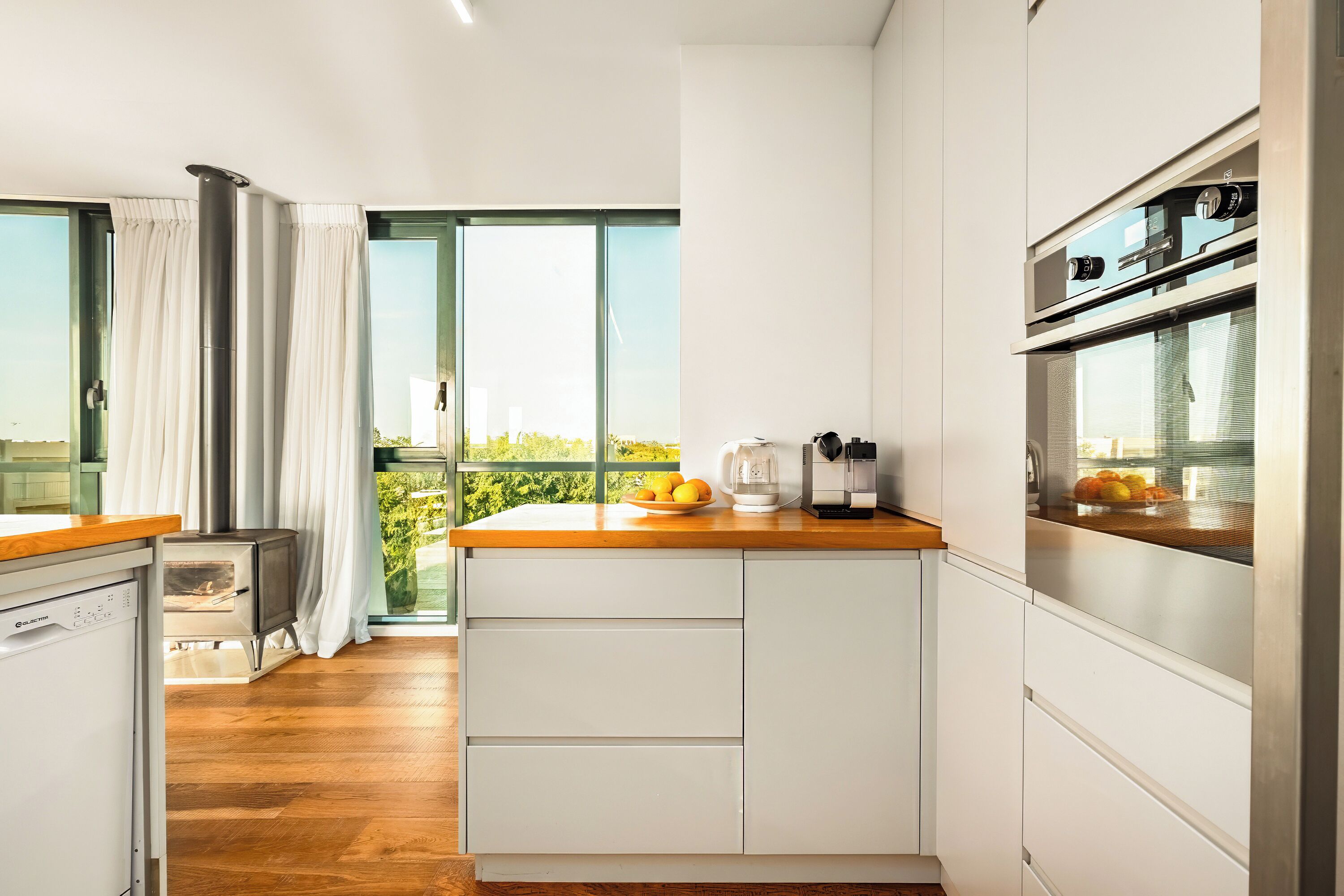 Una cocina moderna con encimera de madera, armarios blancos y horno integrado.