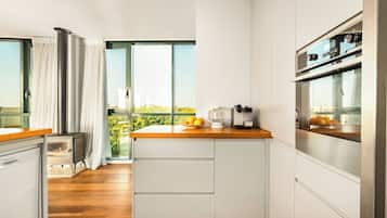 Una cocina moderna con encimera de madera, armarios blancos y horno integrado.