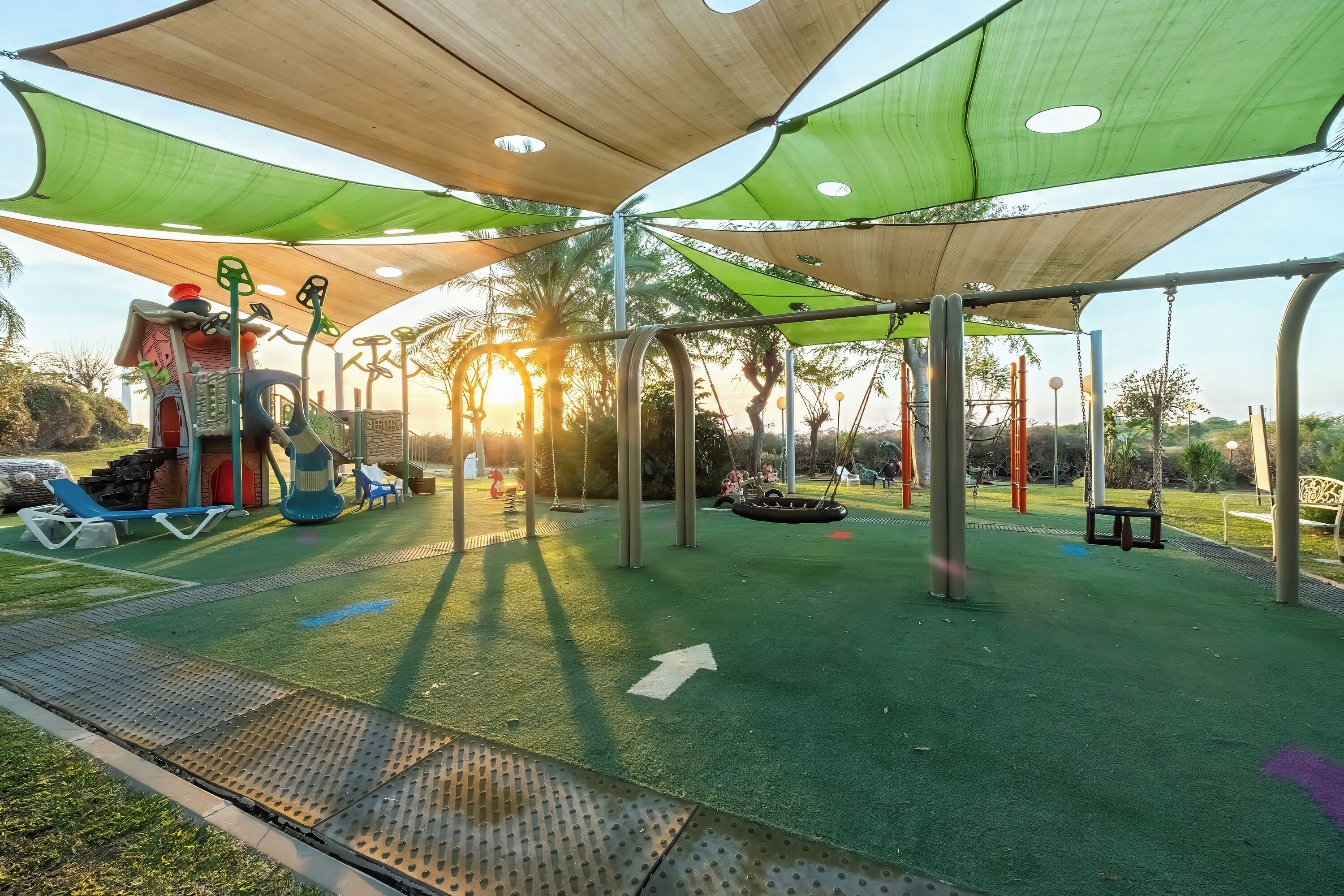 Un parque infantil con un tobogán, columpios y una estructura para escalar.