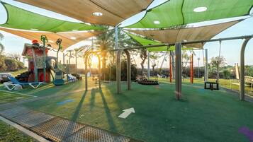 Un parque infantil con un tobogán, columpios y una estructura para escalar.