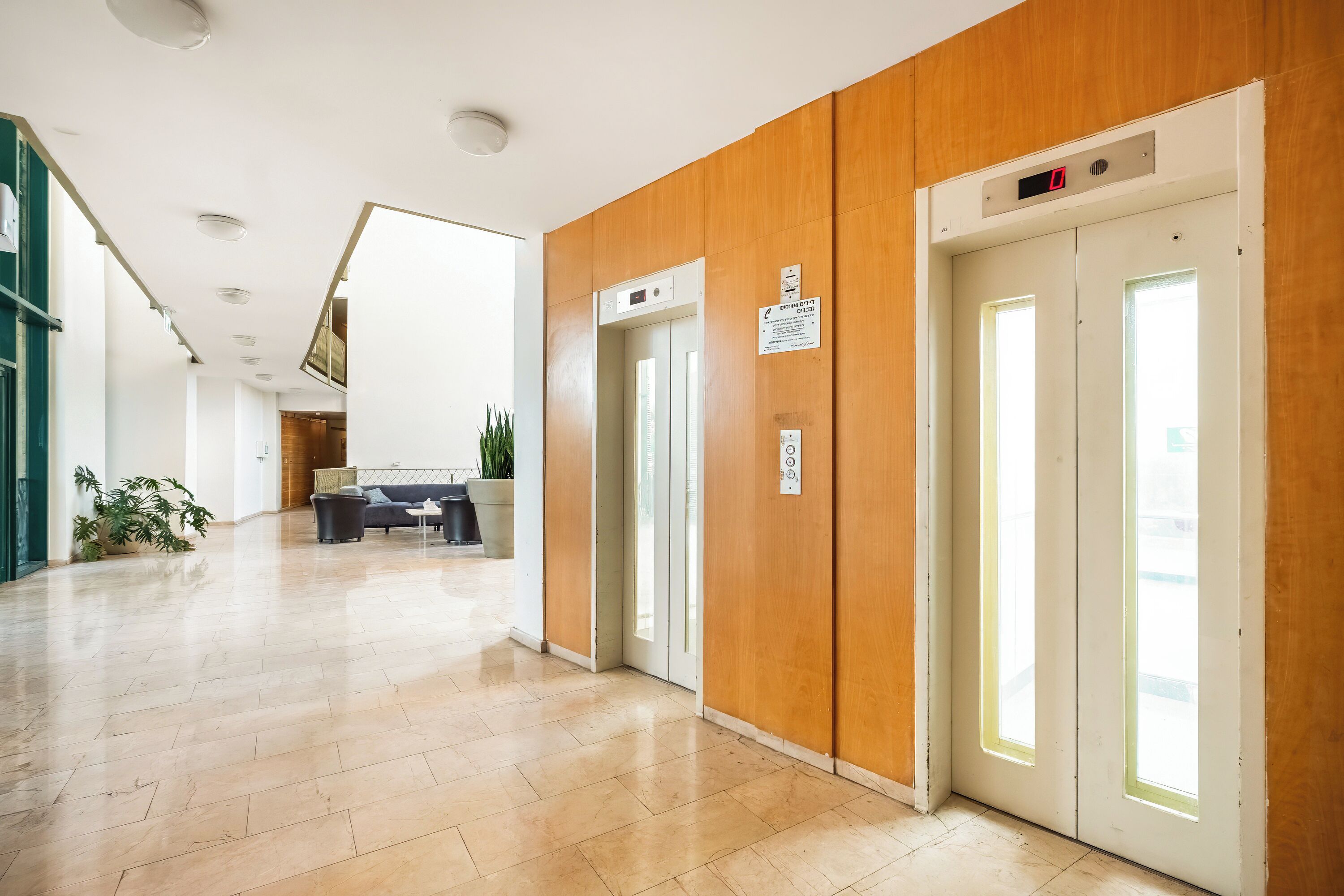 A modern hallway with wooden paneling, a reception desk, and an elevator.