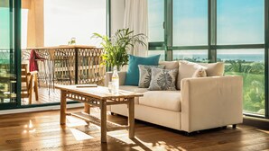 A spacious living room with a large window, a sofa, a wooden coffee table, and a dining area with a chair and table. -  Caesarea Sea Elegant Stay by Sea N' Rent (Hof HaCarmel)