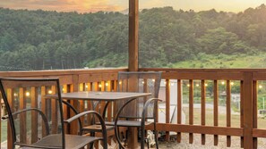 Eine Holzterrasse mit Tisch und Stühlen mit Blick auf eine bewaldete Landschaft.
