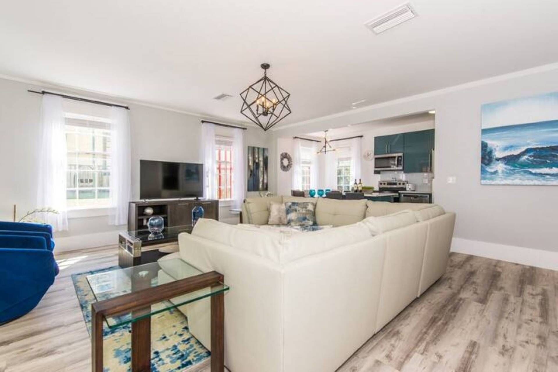 Una sala moderna con un sofá blanco grande, una mesa de centro de vidrio y un televisor.
