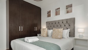 A neatly arranged bedroom with a large bed, a wardrobe, and a bedside table with a lamp. - Modern 3-Bed Home , Canal Views & Parking (Cape Town)
