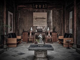A traditional room with a stone table, wooden furniture, and artwork on the walls.