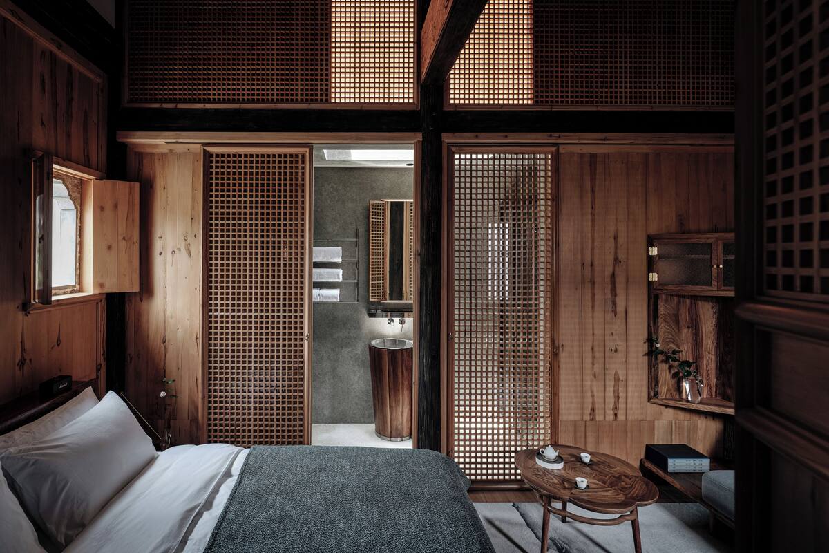 A traditional Japanese-style room with tatami flooring, a low wooden bed, a small table with tea set, and sliding doors.