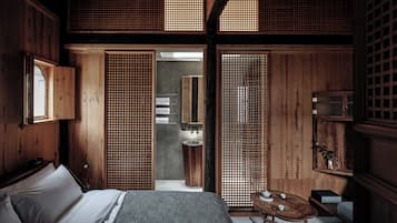 A traditional Japanese-style room with tatami flooring, a low wooden bed, a small table with tea set, and sliding doors.