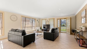 A spacious living room with two sofas, a TV, and a bookshelf.