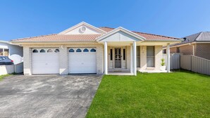 A two-story house with a front porch, two garage doors, and a well-maintained lawn.