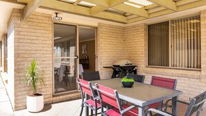 Un espace extérieur aménagé avec une table et des chaises, un barbecue et une plante en pot.