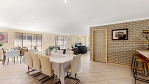 A spacious dining area with a large table, chairs, and a brick accent wall.