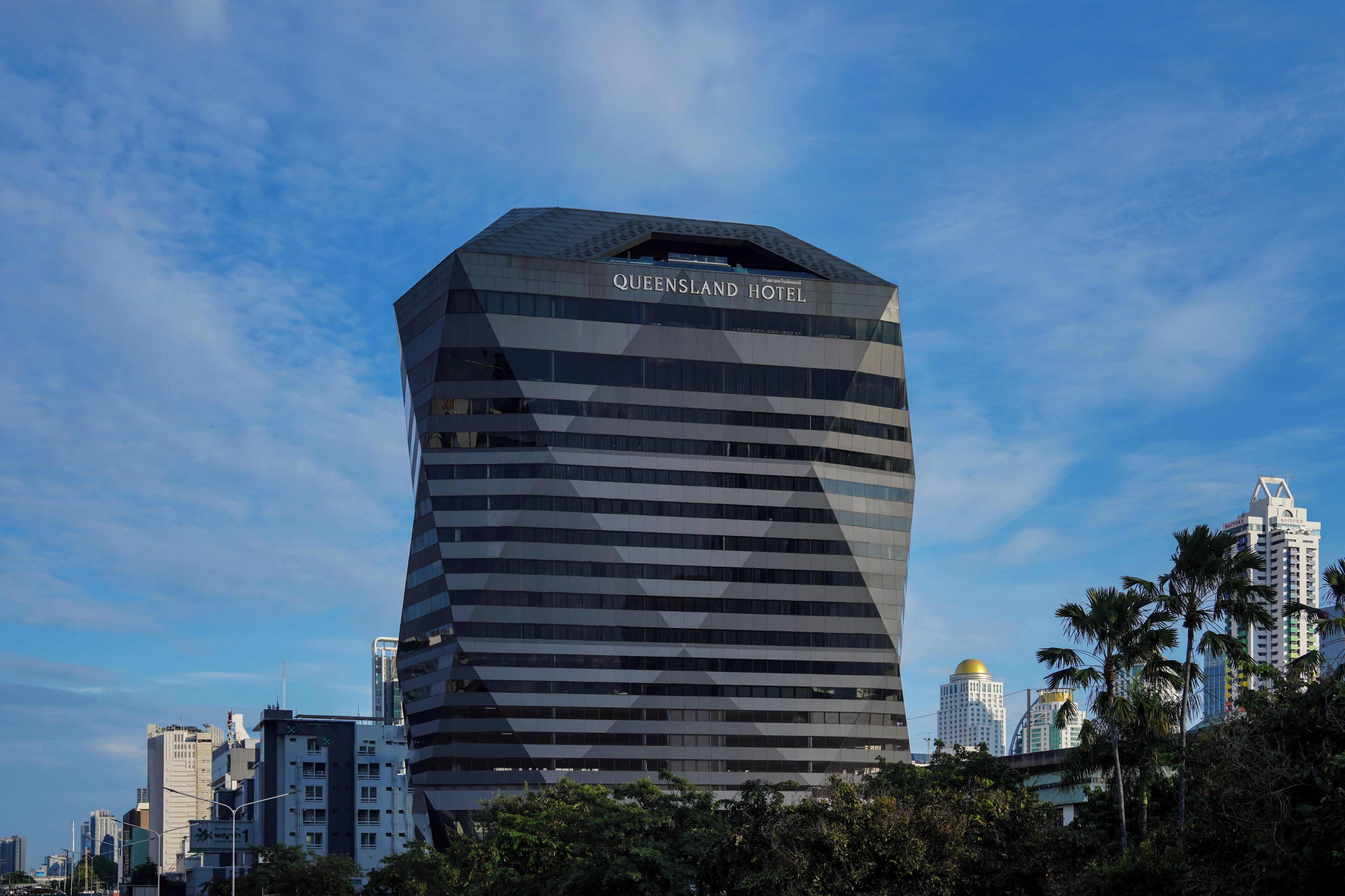 A modern hotel building with a unique angular design, multiple floors, and a prominent sign at the top.