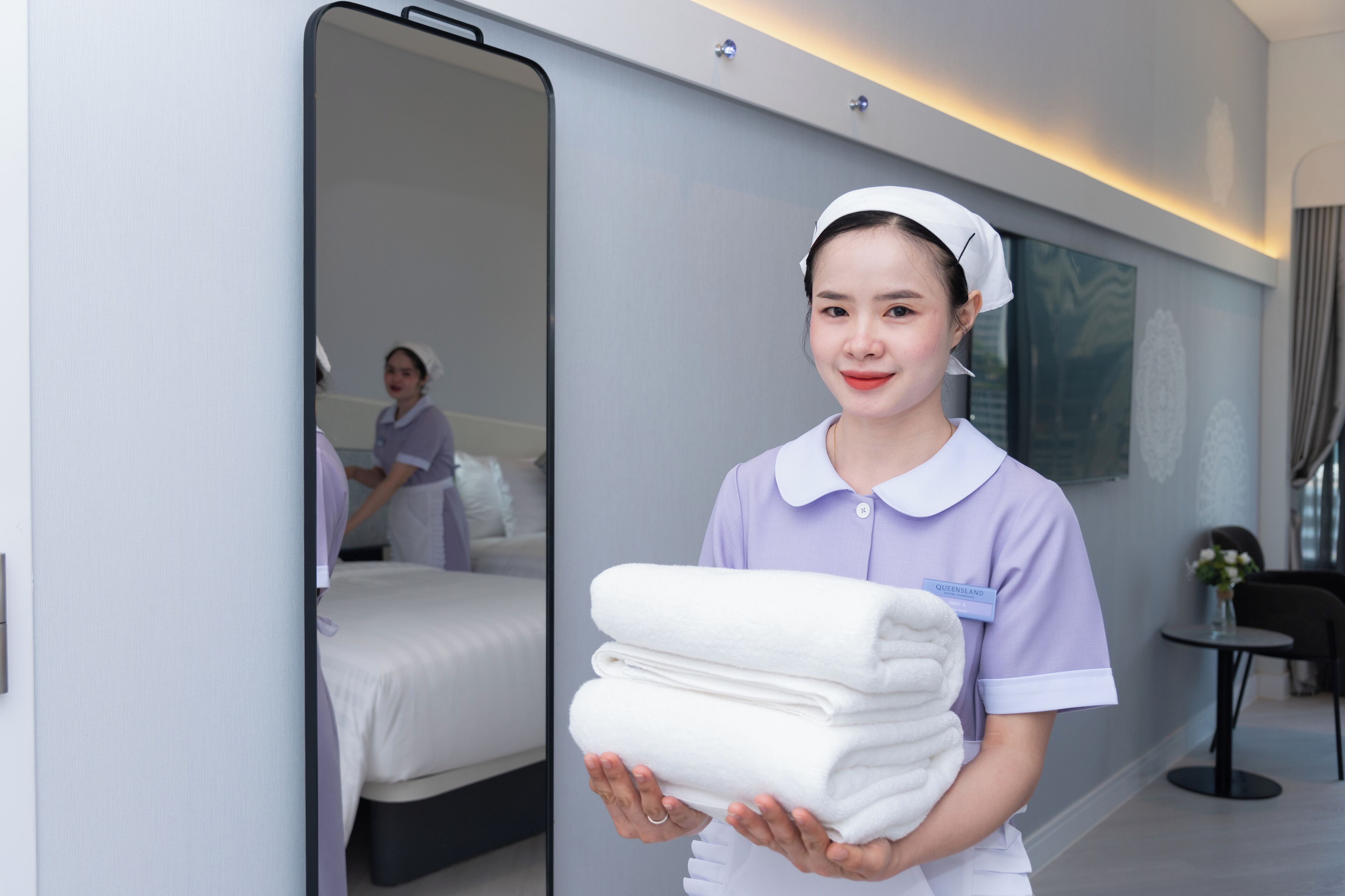 A hotel room with a bed, a bedside table, and a mirror.